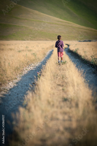 Kid walking alone outdoors. Castelluccio di Norcia, Italy.