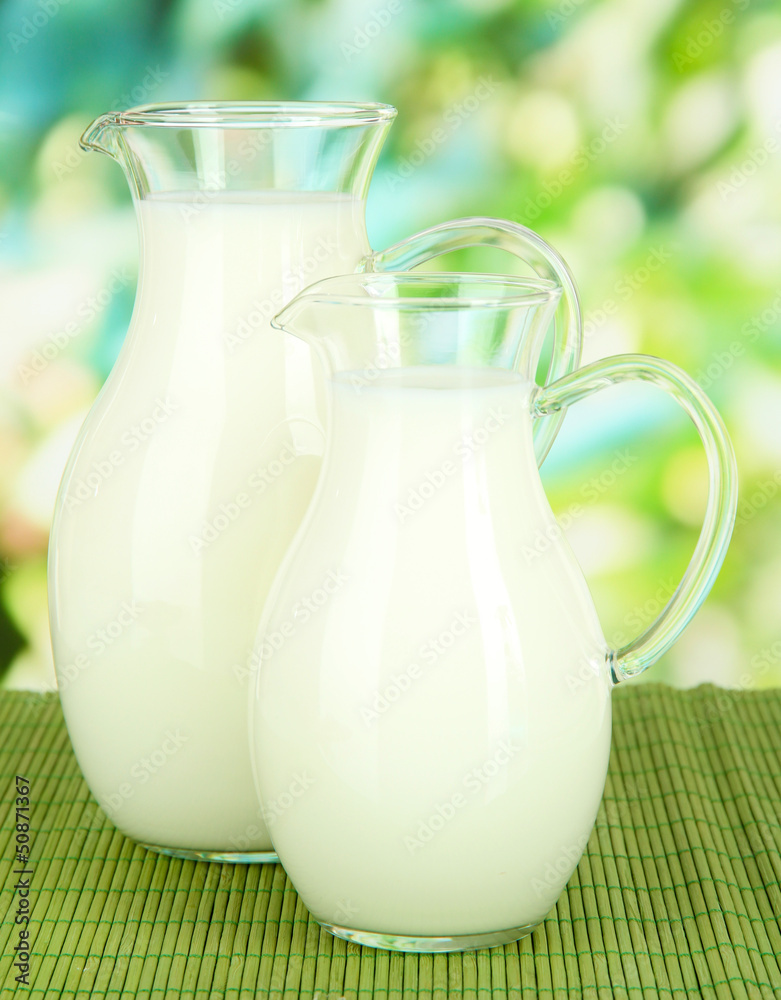 Pitchers of milk on table on bright background Pitchers of milk on table on bright background