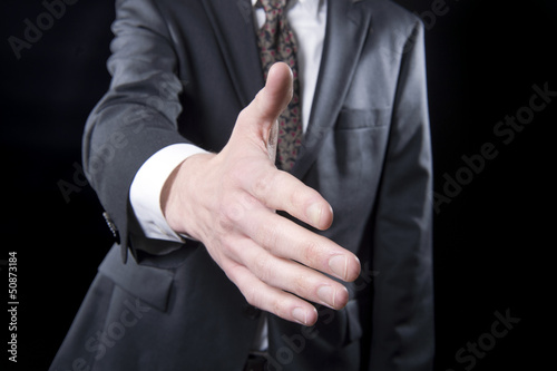 Business executive in suit extends his hand to shake hands © jefftakespics2