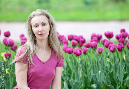 The young beautiful woman in spring park with blossoming tulips