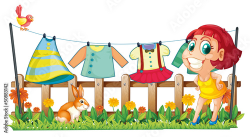 A woman hanging her clothes in the garden with a bunny