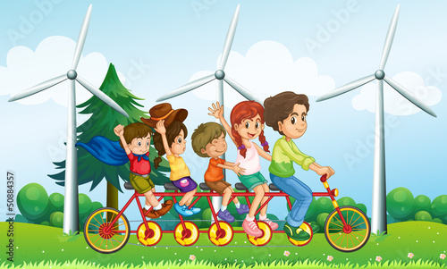 Five kids riding at the bike near the windmills