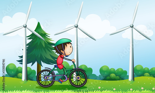 A boy riding with his bike near the windmills