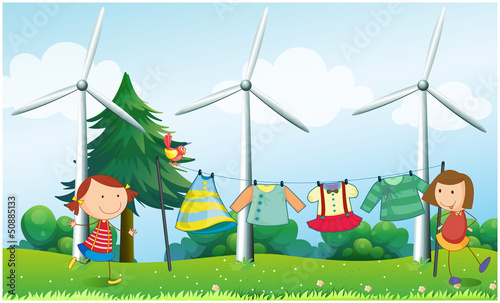 Two girls hanging their clothes near the windmills