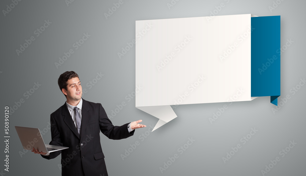 Attractive man holding a laptop and presenting modern origami co Attractive man holding a laptop and presenting modern origami co
