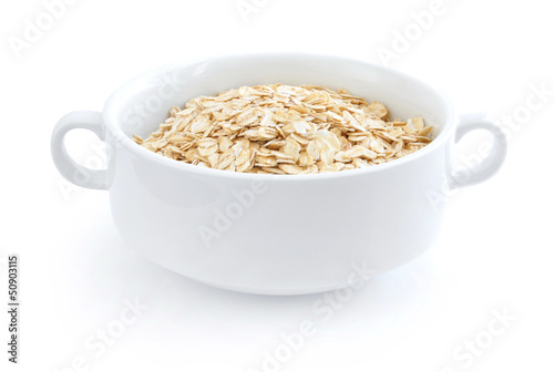 Oat flakes in white bowl on white background