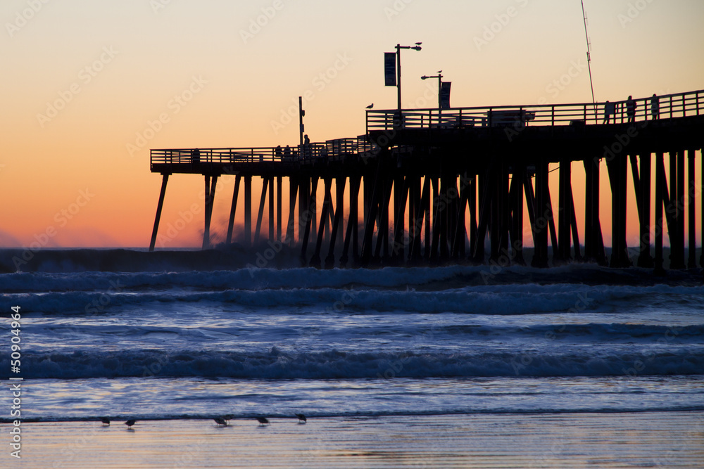 Fototapeta premium Pier at sunset with stormy waves