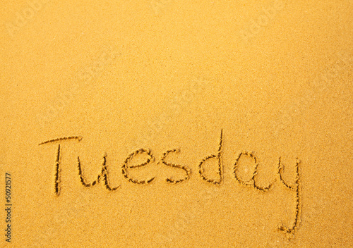 Tuesday, written in sand on beach texture.