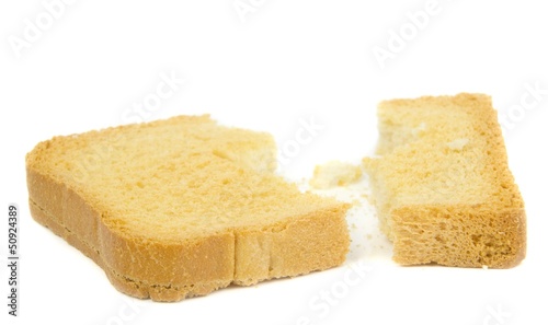 A broken slice of crispbread and crumbs on a white background
