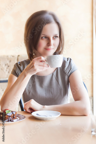 A woman in a restaurant is drinking coffee photo