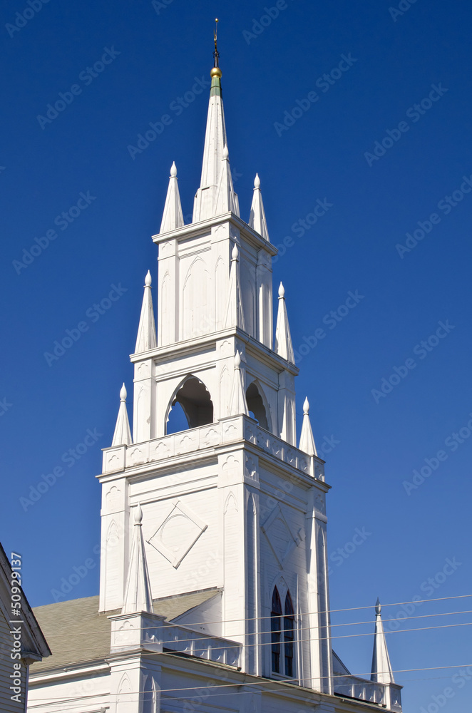 Steeple of historic white church against deep blue sky