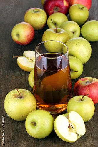Useful apple juice with apples around on wooden table