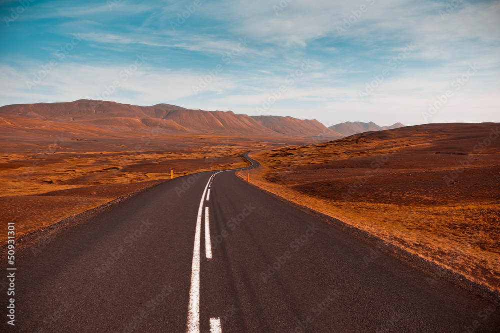 Highway through dry gravel lava field landscape under a blue sum Highway through dry gravel lava field landscape under a blue sum