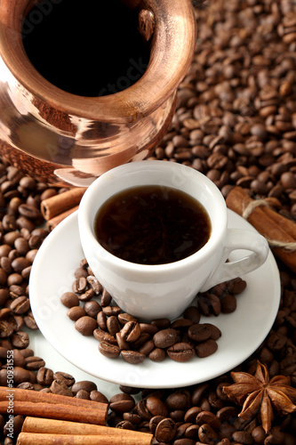 Cup and pot of coffee on coffee beans background