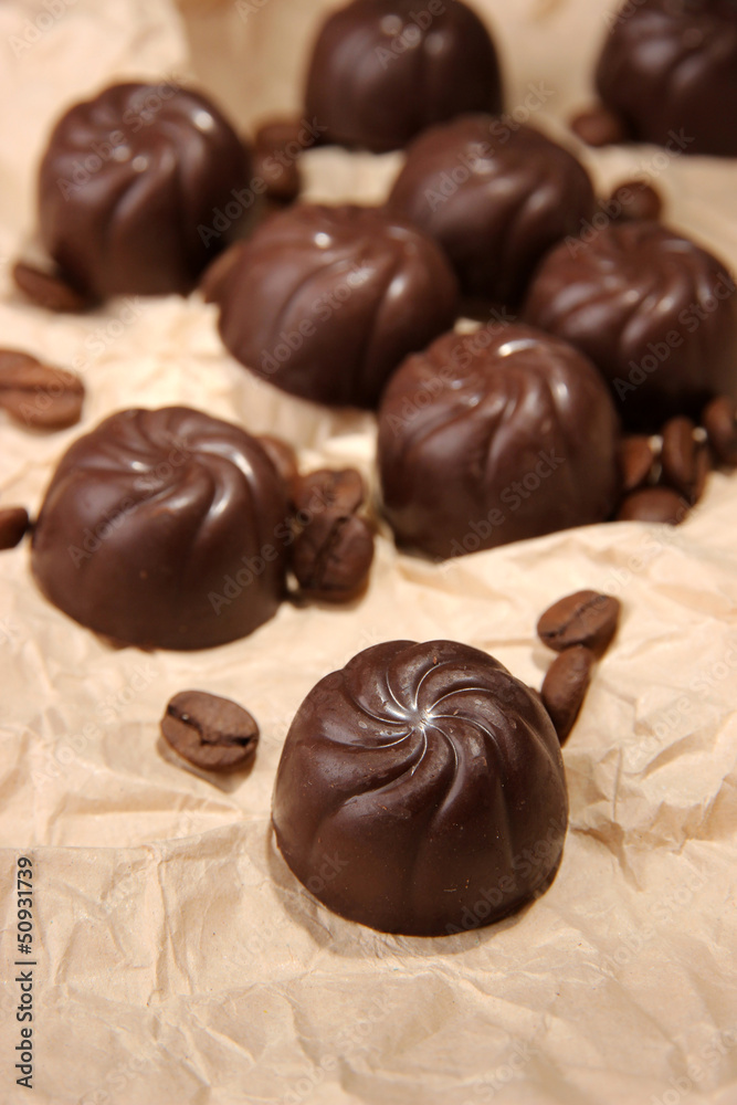 Chocolate candies and coffee beans, on beige paper background Chocolate candies and coffee beans, on beige paper background