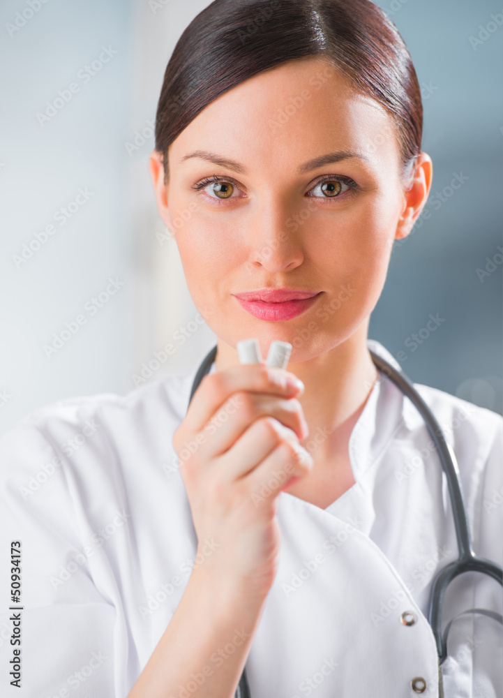Young female dentist doctor holding chewing gum and smiling. Den Young female dentist doctor holding chewing gum and smiling. Den