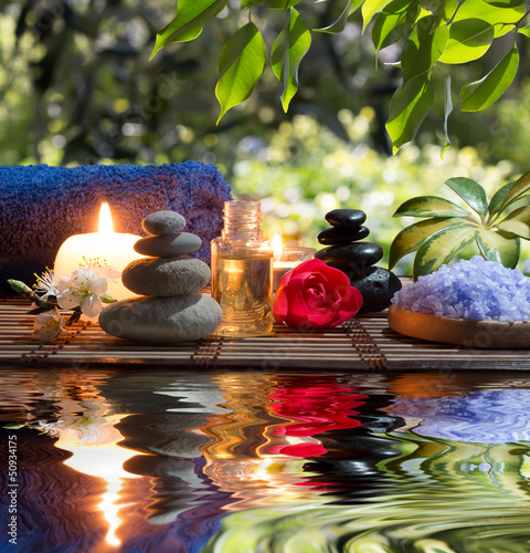 candele, asciugamani, pietre e fiori di mandorle in acqua photo