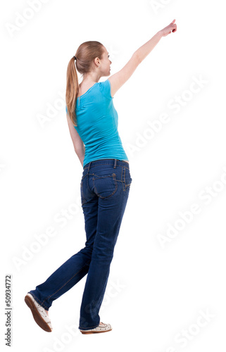 back view of walking woman in jeans and shirt pointing