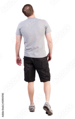 Back view of walking handsome man in shorts and sneakers