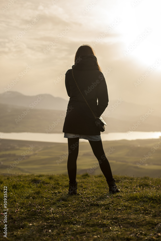 Foto Stock donna di spalle che guarda un paesaggio da una vetta | Adobe  Stock
