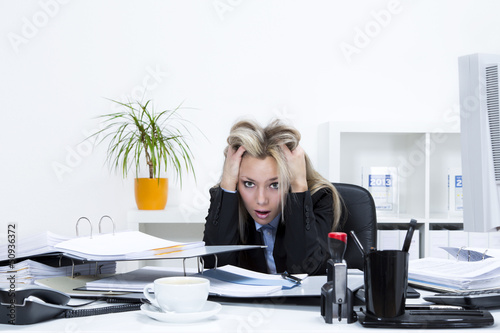 Gestresste Frau im Büro am Schreibtisch photo