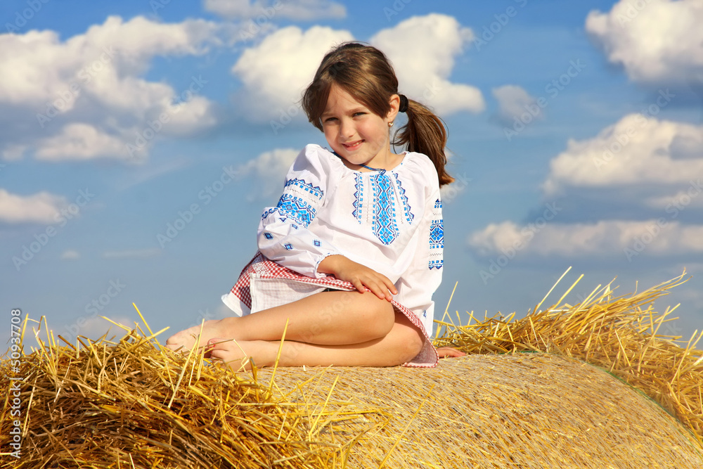 small rural girl on the straw after harvest field with straw bal small rural girl on the straw after harvest field with straw bal