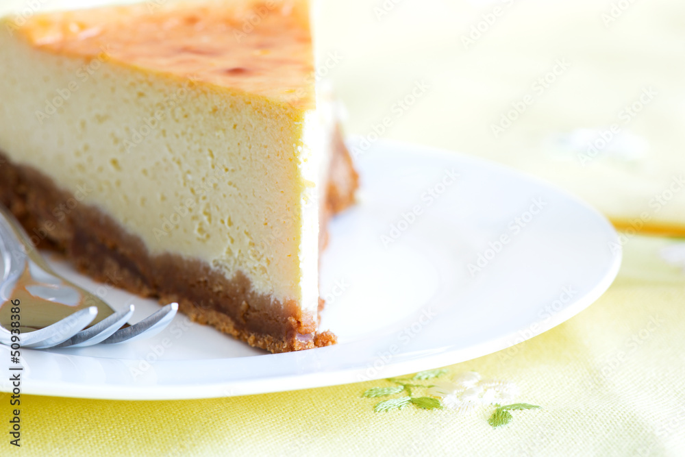 Cheesecake with cake fork in a plate on tablecloth Cheesecake with cake fork in a plate on tablecloth