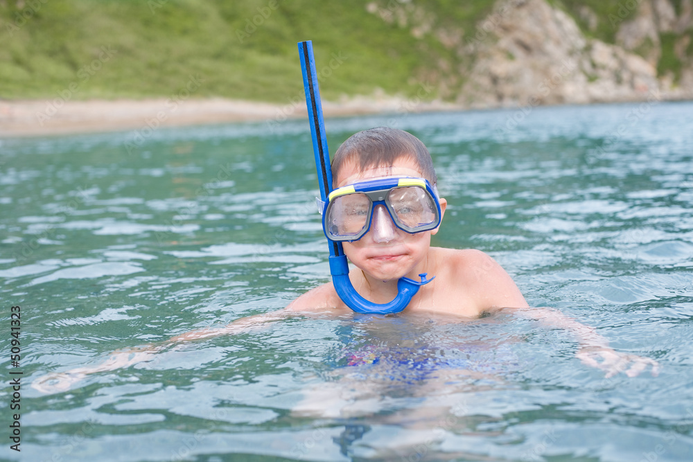 Boy swims in sea a mask for scuba diving.
