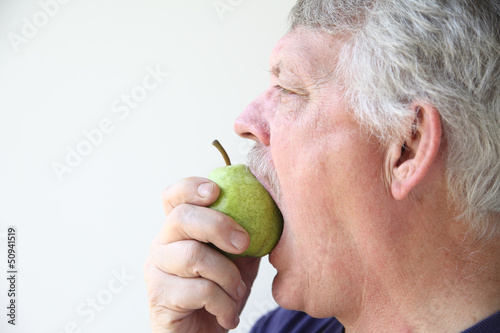 senior man eats a fresh pear