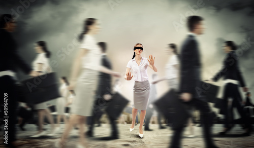 Businesswoman in blindfold among group of people