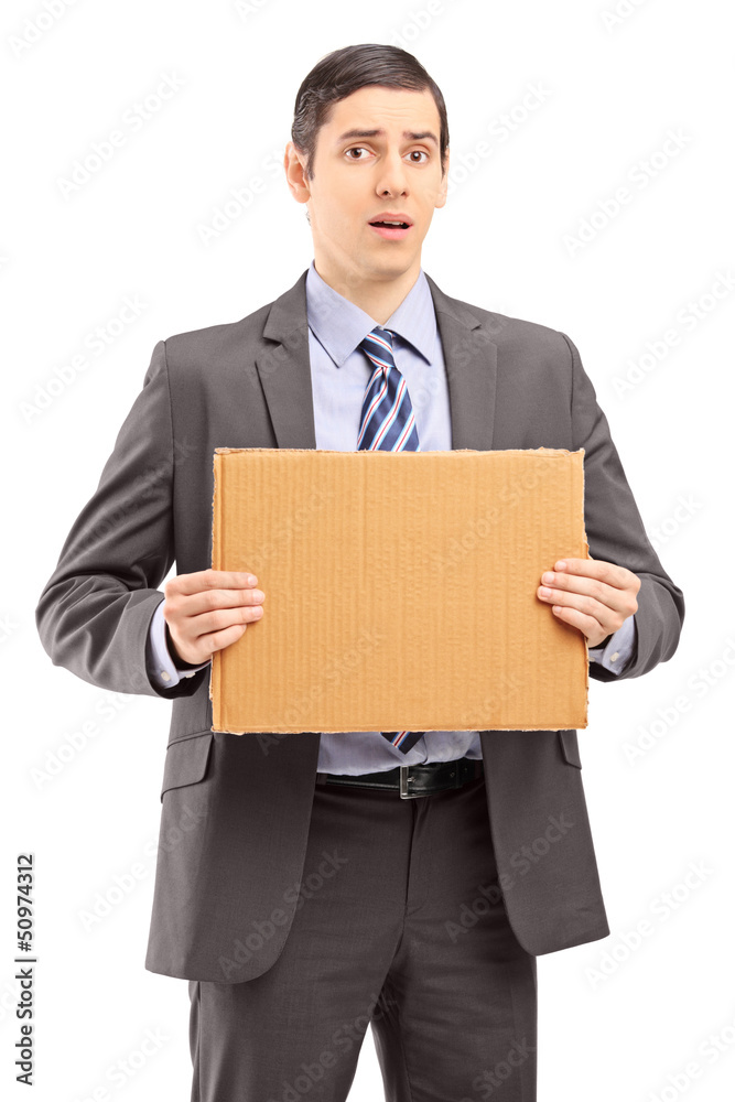 Upset young businessman in suit holding a piece of cardboard Upset young businessman in suit holding a piece of cardboard
