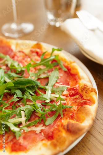 Pizza with arugula on table