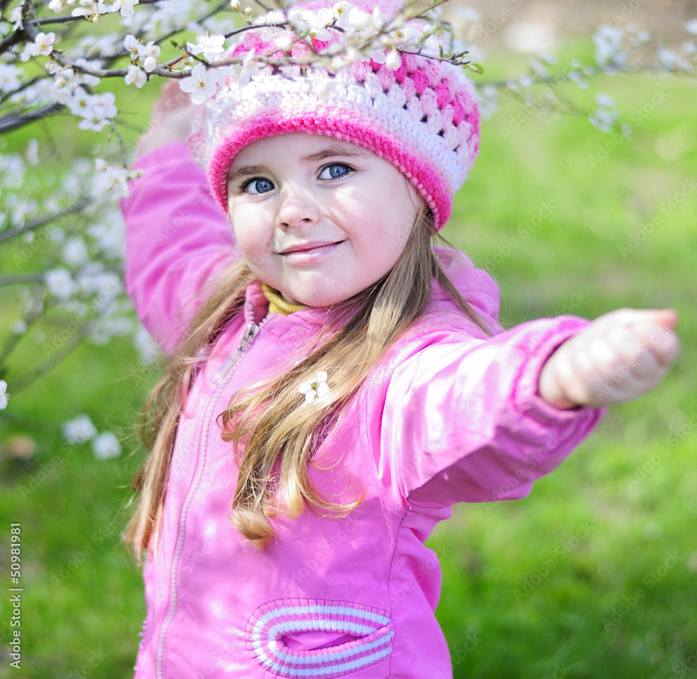 beautiful little girl near a flowering tree