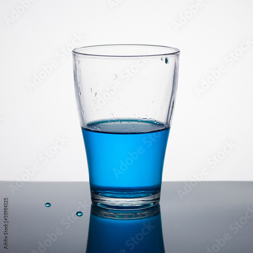 Glass half full of blue liquid