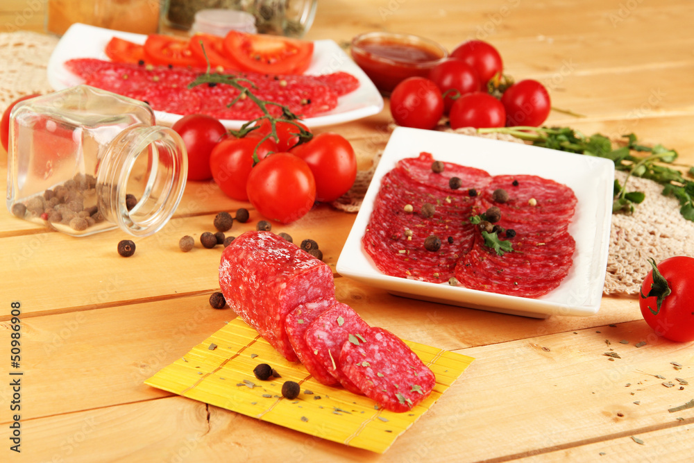 Tasty salami on plates on wooden table close-up Tasty salami on plates on wooden table close-up
