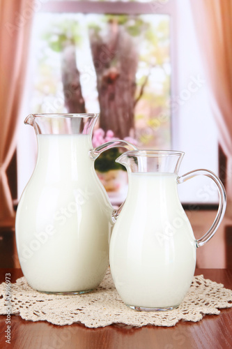 Pitchers of milk on table in room photo