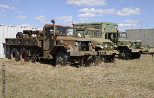 three old army vehicles parked in a grass field