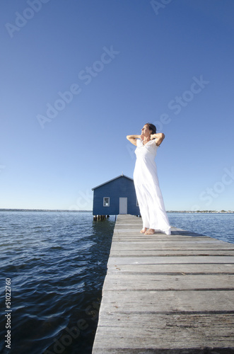 Relaxed woman white dress on boardwalk at sea