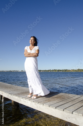 Confident relaxed mature woman white dress ocean