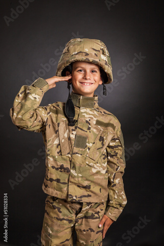 Saluting soldier. Young boy dressed like a soldier