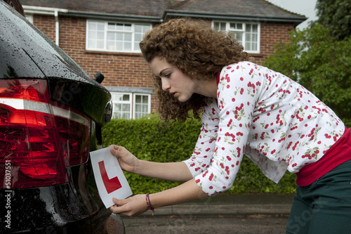 Young female driver attaching a L plate to car
