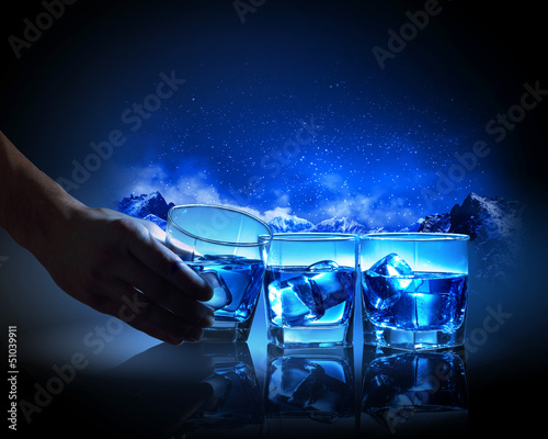 Three glasses of blue liquid with ice