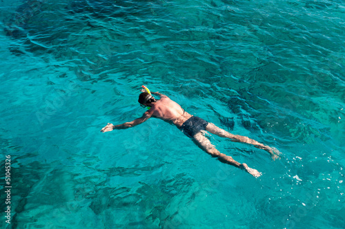 Young man with scuba equipment laying on sea surface