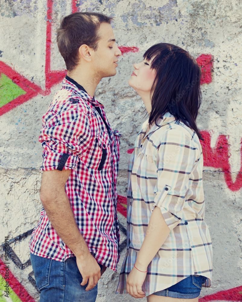 Young couple kissing near graffiti background. Young couple kissing near graffiti background.