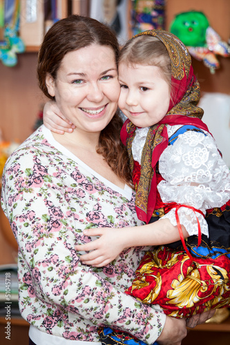 Happy mother holding small girl in Russian traditional clothes