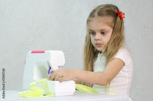 Девочка шьет на швейной машинке