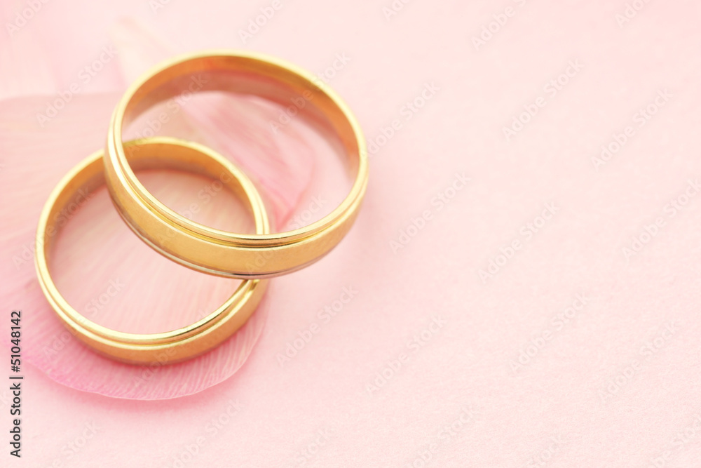 Wedding rings with flower petals on pink background Wedding rings with flower petals on pink background