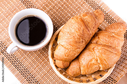Fototapeta Naklejka Na Ścianę i Meble -  Fresh French croissants in a basket and cup of coffee