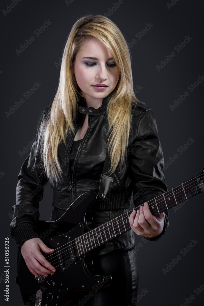 Fototapeta premium Sexy young blonde dressed in black leather playing electric gui