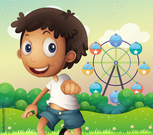 A boy standing across the ferris wheel